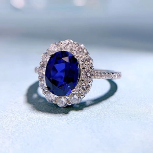 Elegant 7x9mm oval blue sapphire ring with halo diamonds on a polished silver band