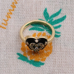 Detailed close-up of a gold-plated heart ring featuring black enamel and evil eye motif