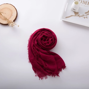 Detail of burgundy cotton linen scarf with soft crinkle texture and frayed fringe edges