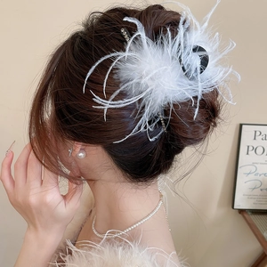 Detail view of elegant white feather hair claw with rhinestones on a back bun hairstyle