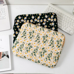 Close-up of quilted daisy embroidery on canvas laptop sleeves with elegant floral details