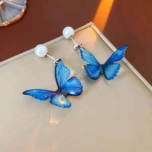 Detailed macro view of gradient blue resin butterfly earrings with glitter and pearl