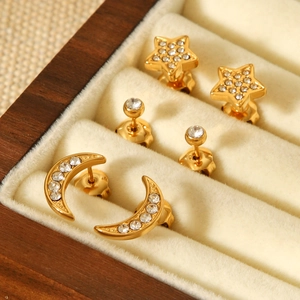 Macro shot of gold-plated star and moon stud earrings set with zircon in a wooden box