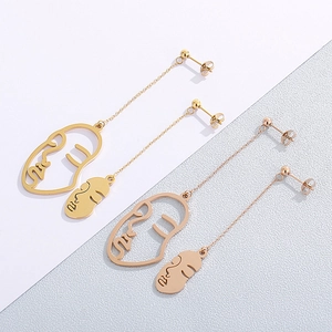 Longues boucles d'oreilles visage abstrait en or et or rose au look artistique