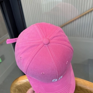 Close-up of rose pink baseball cap with white CD embroidery and detailed stitching