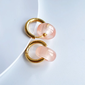 Detailed view of 18k gold plated hoop earrings with translucent pink stone charms