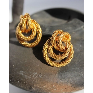 Vintage golden spiral twist earrings with double ring knot design on stone background