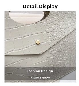 Close-up of white crocodile embossed leather handbag with golden metal buckle