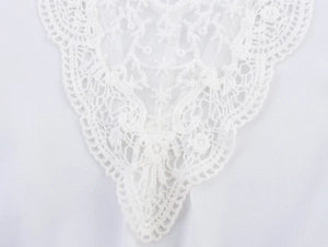 Close-up of white lace embroidery detail with floral patterns on lightweight chiffon fabric