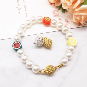 Detail of pearl bracelet with golden rhinestone magnetic clasp and cat pendant charm