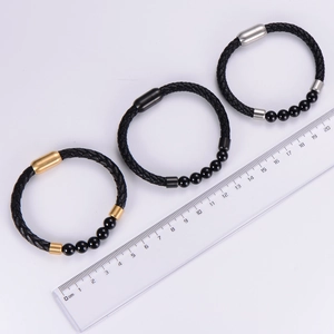 Dettaglio di bracciali in pelle intrecciata nera con perline di onice e chiusura magnetica