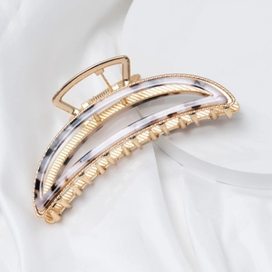 Detail of a gold metal moon-shaped hair claw clip with a stylish tortoiseshell finish