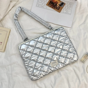 Close-up of silver quilted laptop bag with heart bow detailing and fabric label