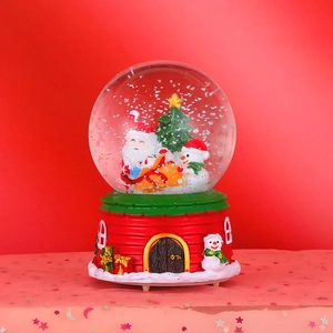 Detail of Christmas crystal ball with Santa, snowman and resin house base on red background