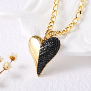 Gros plan d'un pendentif cœur en or 18 carats avec zircons noirs et métal poli