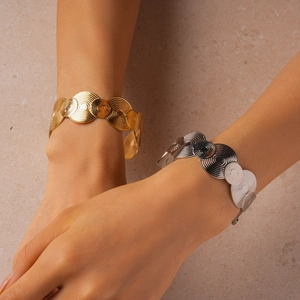 Detailed view of wide gold and silver open bracelets with spiral textured geometric patterns