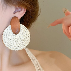 Détail de boucles d'oreilles bohèmes en raphia tissé avec clous en bois sur mannequin
