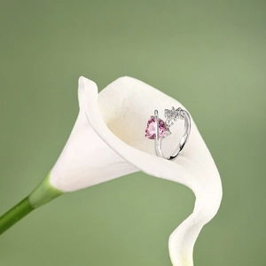Macro shot of S925 silver ring with pink heart gem and pearl on a white flower