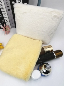 Large macaron plush makeup bags in white and yellow displayed with cosmetics
