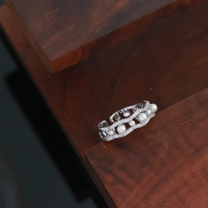 Macro shot of silver wave ring with five white pearls and sparkling zircon pavé