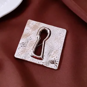 Vintage silver square brooch with hammered texture and keyhole cutout on silk