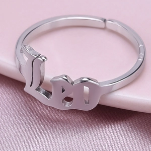 Macro shot of polished silver Leo zodiac letter ring on soft purple fabric background