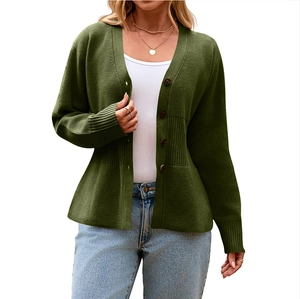 Close-up of dark green knitted cardigan showing rib-knit waist and long button cuffs