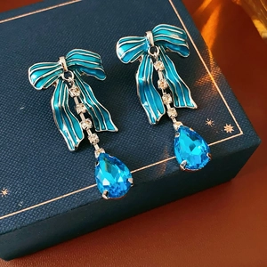 Dettaglio degli orecchini con fiocco blu smaltato e cristallo a goccia su portagioie