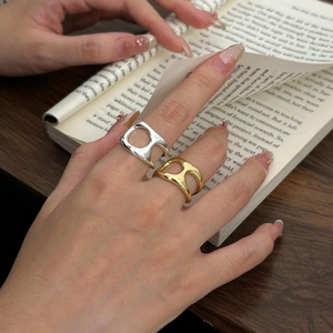 Close-up of minimalist geometric cutout rings in gold and silver on a book background