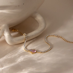 Close-up of a gold-plated tennis bracelet featuring pink and clear heart-shaped zircons