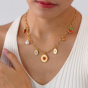 Detail of gold titanium necklace with cherry, heart and pearl charms on a model neck