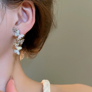 Silver butterfly tassel earrings with shimmering mother of pearl detail on model