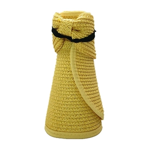 Dettaglio di cappello di paglia giallo pieghevole con fascia elastica e fiocco