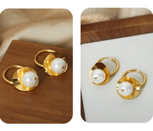Close-up of gold-plated hoop earrings featuring vintage white pearl drop details