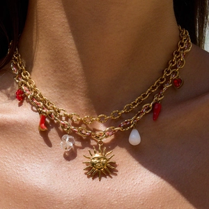 Multilayer gold chain necklace with colorful sun, heart, and chili charms on a model