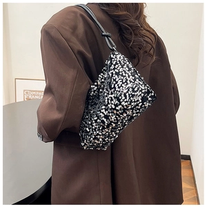 Detail of silver sequin shoulder bag with black leather knotted strap on brown blazer