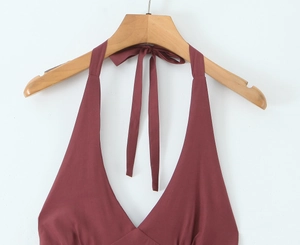 Detail of burgundy halter neck dress with deep V-neckline and tie fastener on white background
