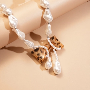 Close-up of baroque pearl necklace featuring a resin leopard print bow pendant detail