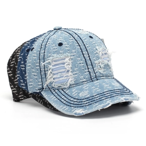 Detailed view of distressed denim baseball caps with ripped holes in various colors