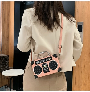 Detailed view of pink vintage radio-shaped crossbody bag worn with beige blazer