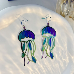 Detailed close-up of iridescent jellyfish earrings with rainbow laser finish on white tray