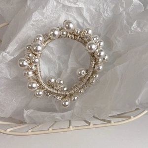 Detailed close-up of premium pearl hair tie with elastic beige band in aesthetic setting