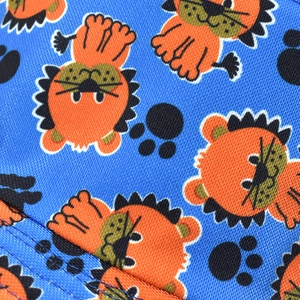 Macro shot of cotton fabric featuring a cute cartoon lion and paw print pattern on blue