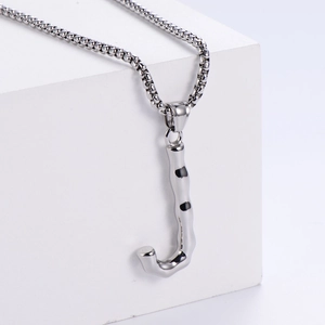 Détail du pendentif lettre J argenté avec texture fluide sur une chaîne maille vénitienne