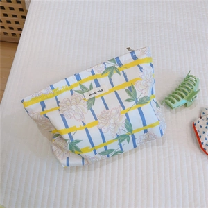 Detailed close-up of a floral cotton makeup bag with yellow stripes and simple wish label