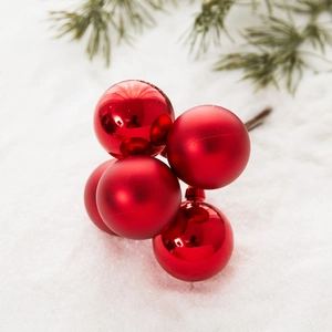 Red Christmas berry cluster pick with shiny and matte ornaments on snowy background