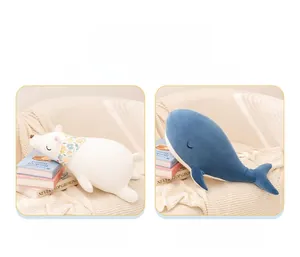 Close-up of plush polar bear with floral scarf and blue whale doll on a soft sofa