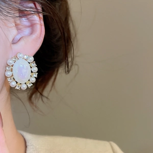 Close-up of model wearing vintage oval pearl earrings with sparkling rhinestones