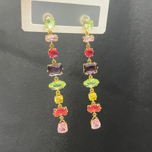 Macro view of teardrop colorful crystal tassel earrings on a textured black background