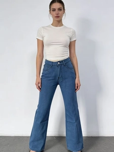 Dettaglio dei jeans a zampa a vita alta con stampa di farfalle blu e trama in denim